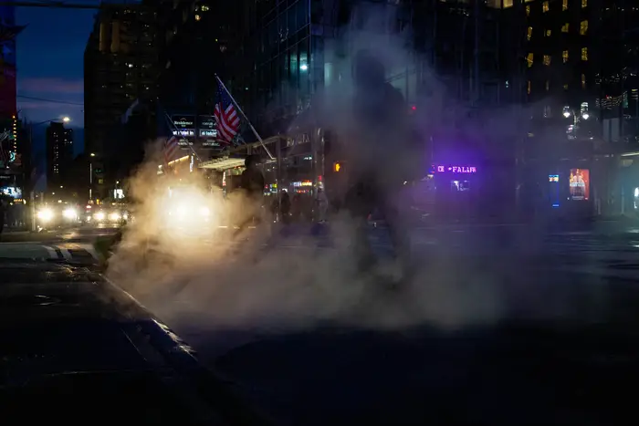 A photo of a person walking through smoke at night on Broadway